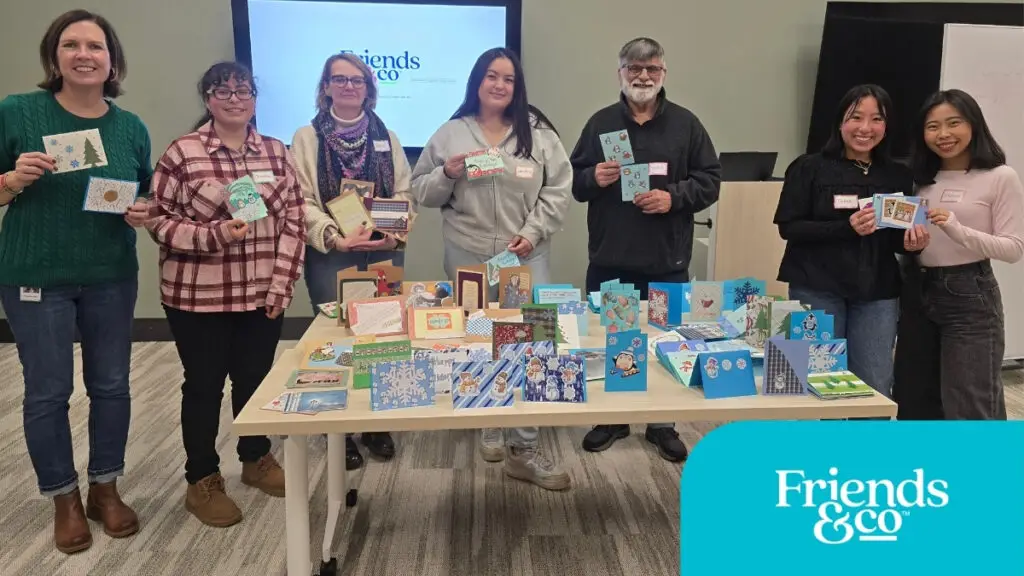 Volunteers making cards for older adults with Cards Connect at Friends & Co non-profit in the Twin Cities standing showing their cards