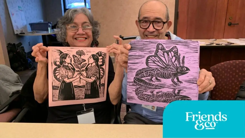 Two Older Adults holding their art projects during Friends & Co Cafe Y Conversaciones