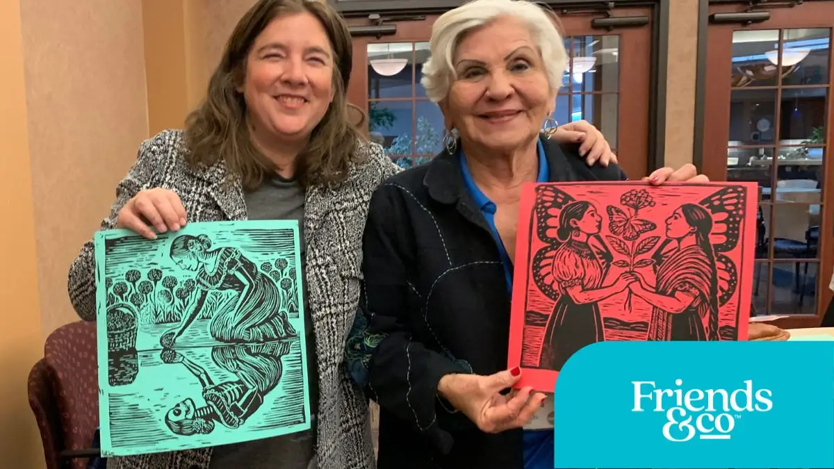 Older Adult showing her print making with COMPAS Teaching Artist Constanza Carballon at Friends & Co Cafe Y Conversaciones