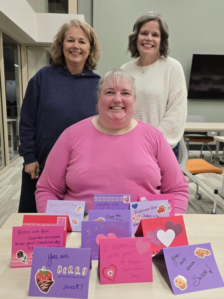 Three women volunteering together at Friends & Co card making event