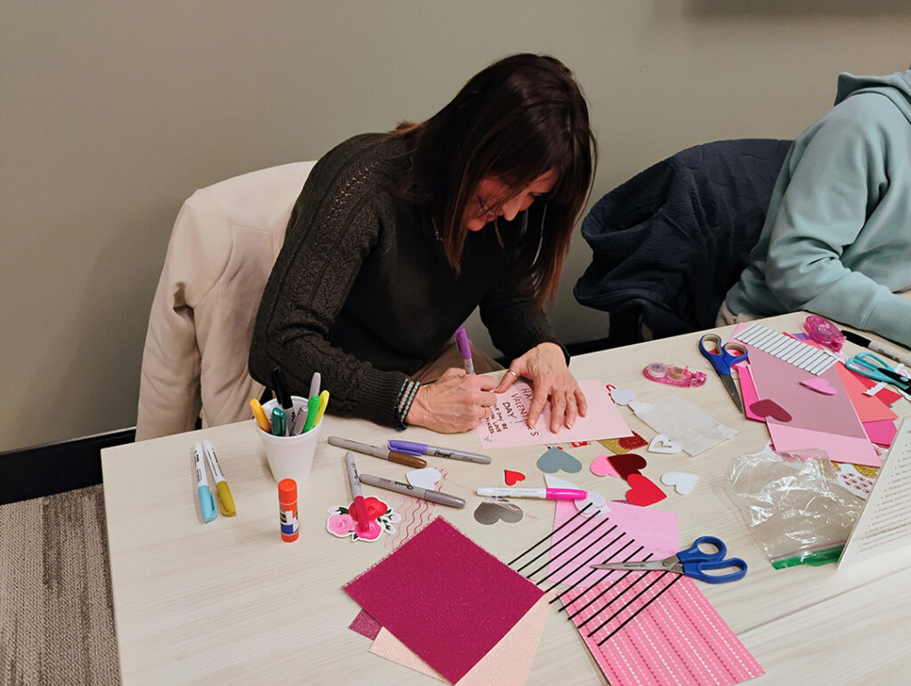 Woman volunteer hand making a valentines day card for Friends & Co