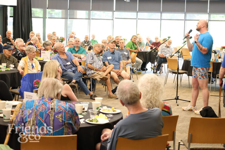Older Twin Cities gay and lesbian seniors listneing to singer with Gay Men's Chorus "Outloud"