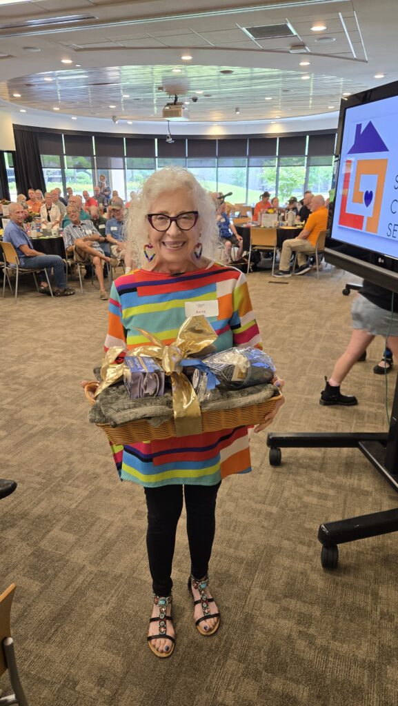 Brightly dressed Older adult holding his winning themed gift basket